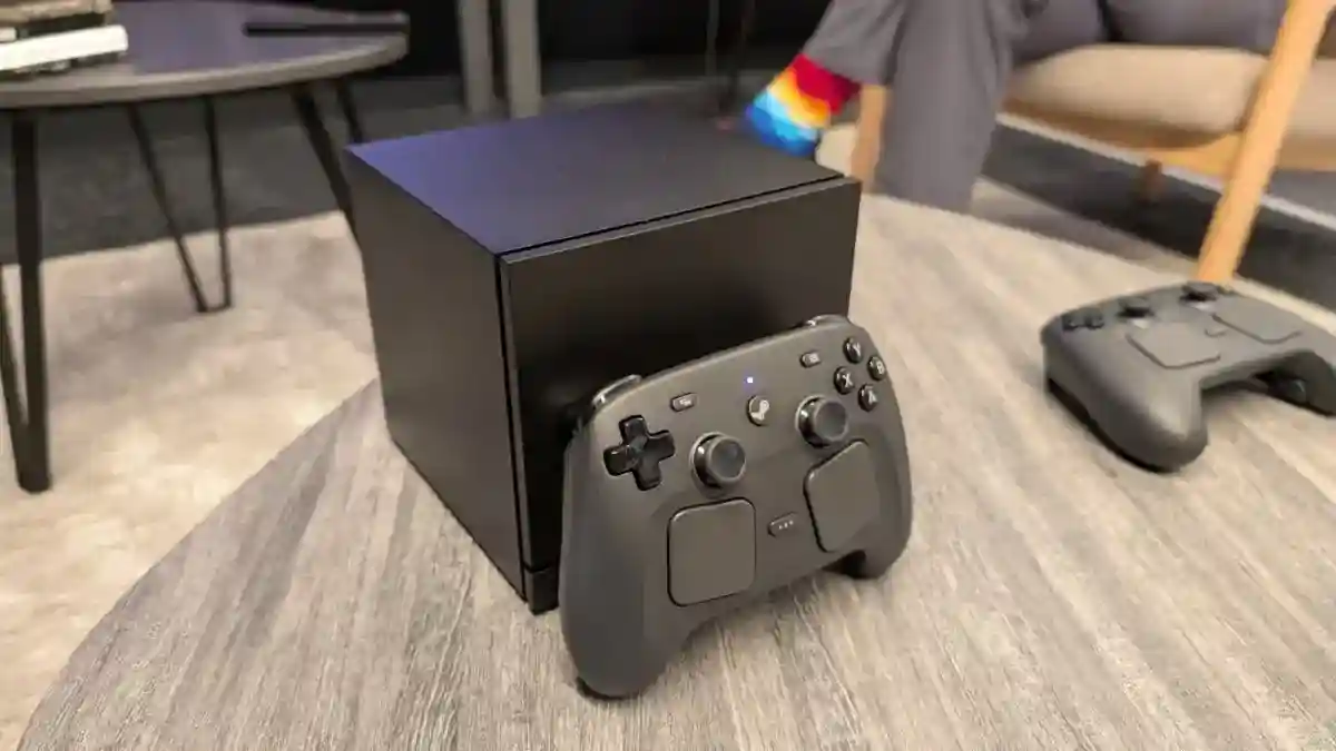Console Steam Machine de Valve posée sous une télévision avec manette Steam Controller